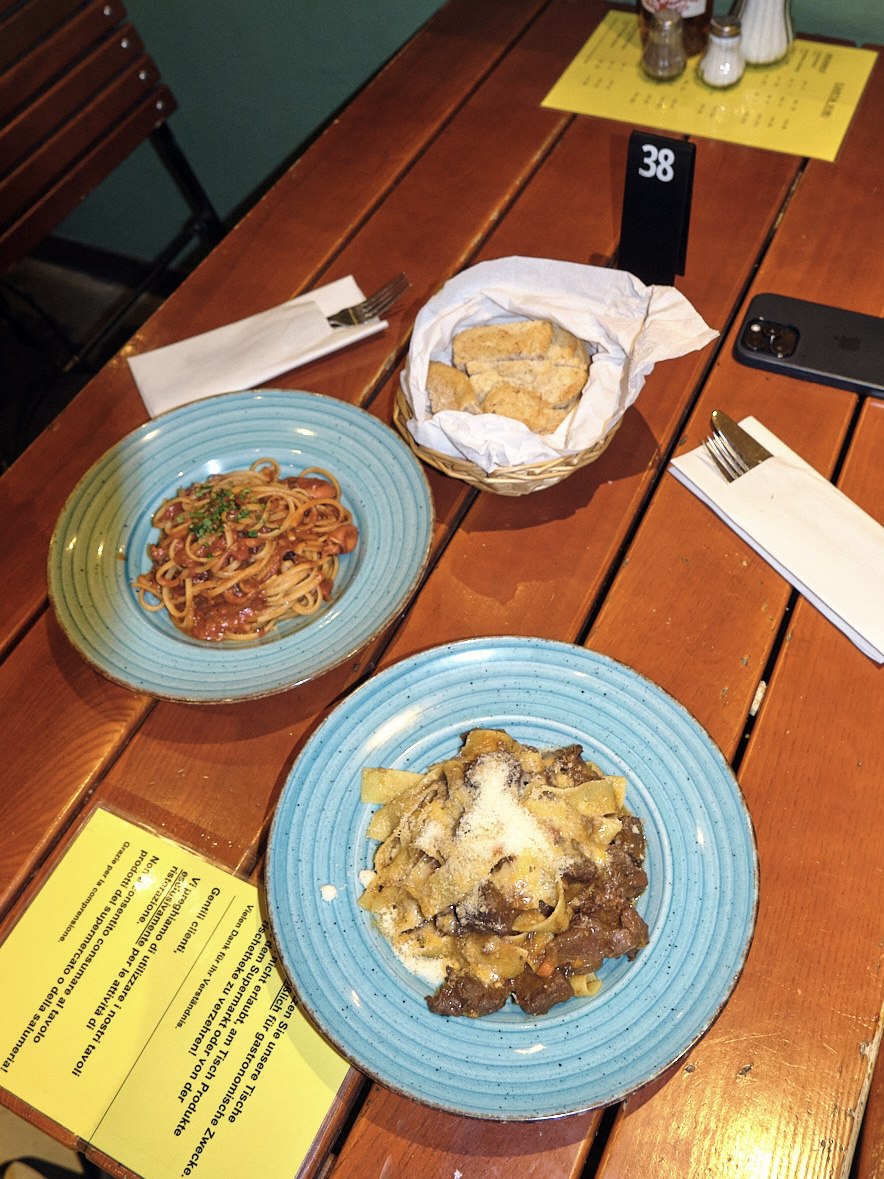 Pappardelle with venison ragù and a tomato linguine with a bread basket on a wooden table at Centro Italia